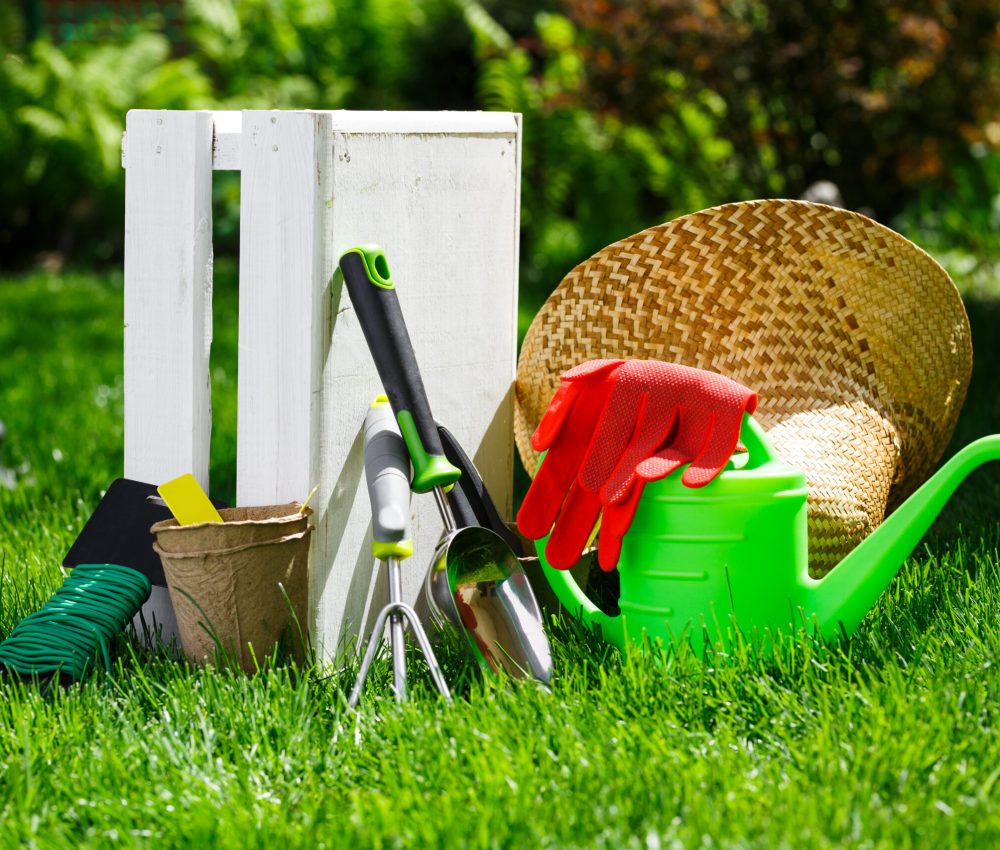 Gardening tools and a straw hat on the grass in the garden